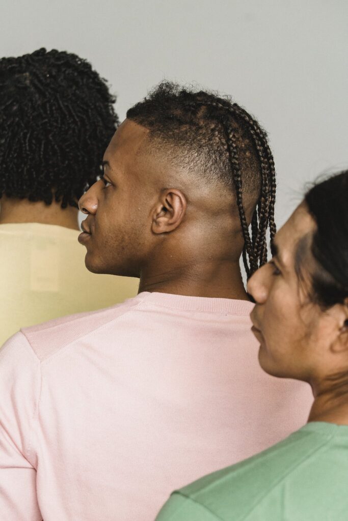 Back view of crop multiracial male models in stylish outfits standing close and looking away