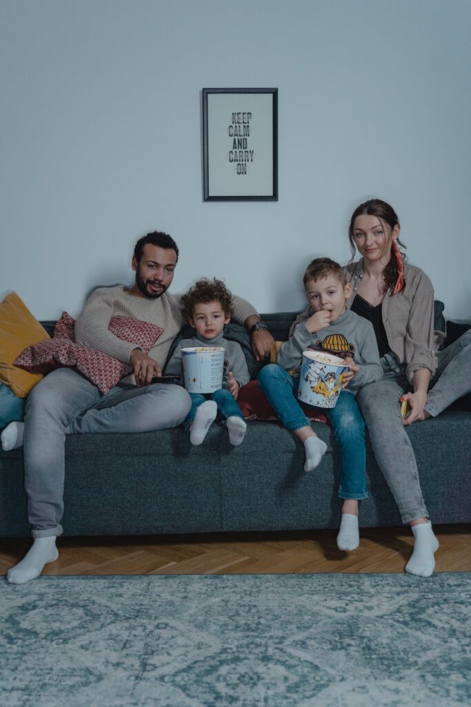 A Happy Family eating Popcorn while Sitting on the Couch
