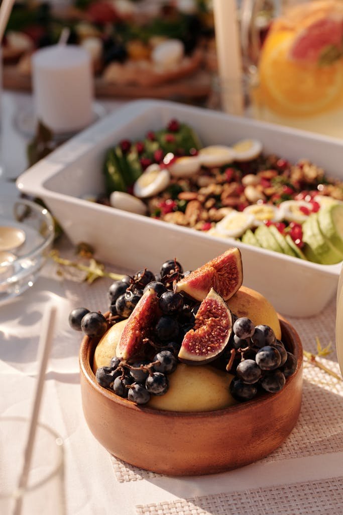 High angle of ceramic plate with fresh fruits and berries on table with various snacks